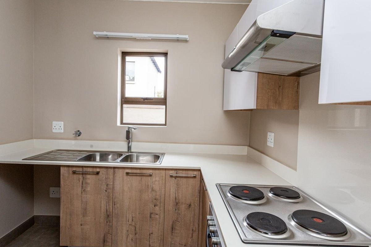 Modern kitchen featuring wood-look cabinetry, stone countertops, a double bowl sink, and built-in electric cooking appliances.