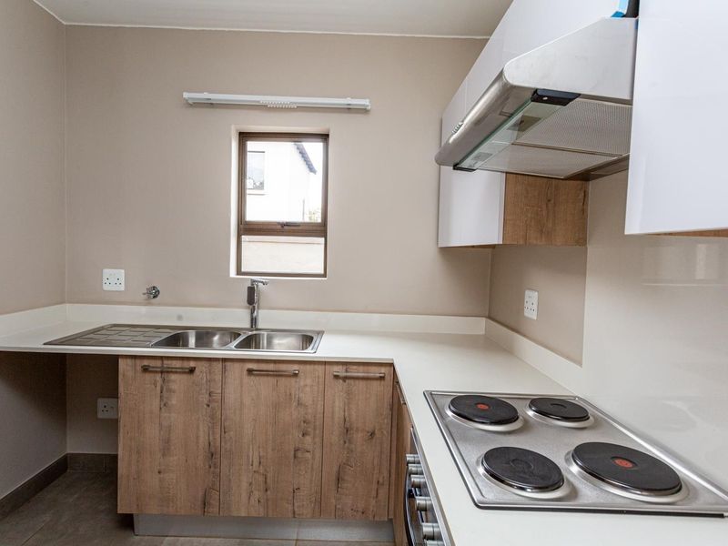 Modern kitchen featuring wood-look cabinetry, stone countertops, a double bowl sink, and built-in electric cooking appliances.