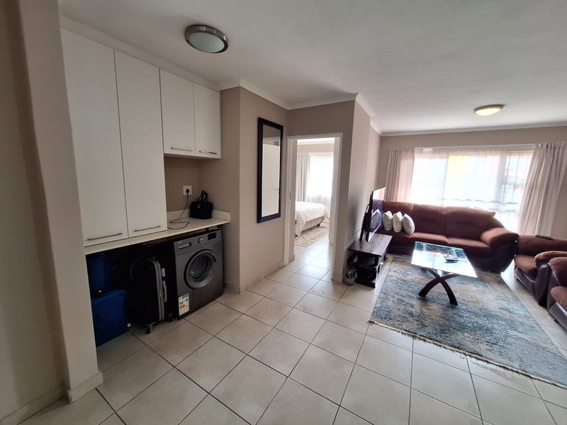 Open plan living area featuring tiled flooring, built-in cabinetry with laundry space, and direct access to the bedroom.