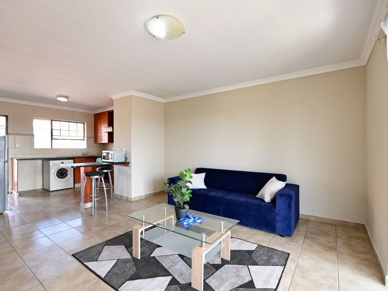 Open-plan living area featuring tiled floors, a functional kitchen with built-in cabinetry, and a breakfast counter, creating a versatile and connected living space.