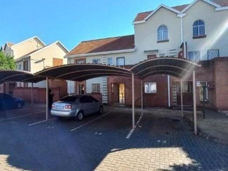 Exterior view of the apartment complex featuring covered parking bays and paved driveway access.