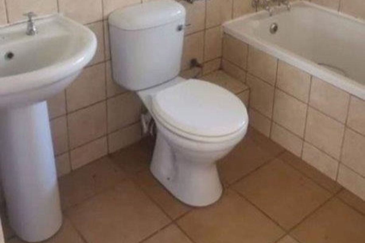 A functional bathroom featuring a pedestal basin, standard toilet, and a built-in bathtub with tiled wall and floor finishes.