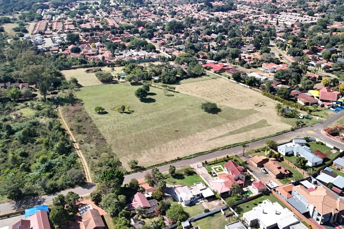Aerial view of a large, undeveloped land parcel situated within an established residential neighborhood, offering significant potential for future development.