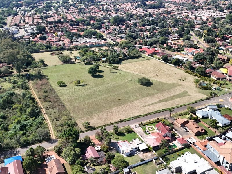 Aerial view of a large, undeveloped land parcel situated within an established residential neighborhood, offering significant potential for future development.