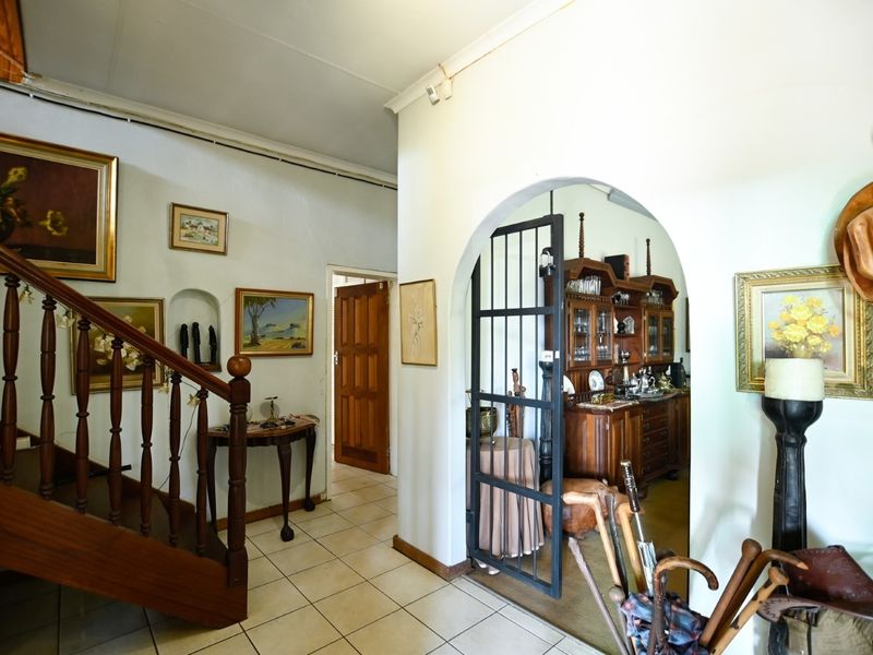 Entrance hallway featuring a wooden staircase, tiled flooring, and an arched doorway leading to an adjacent living space.