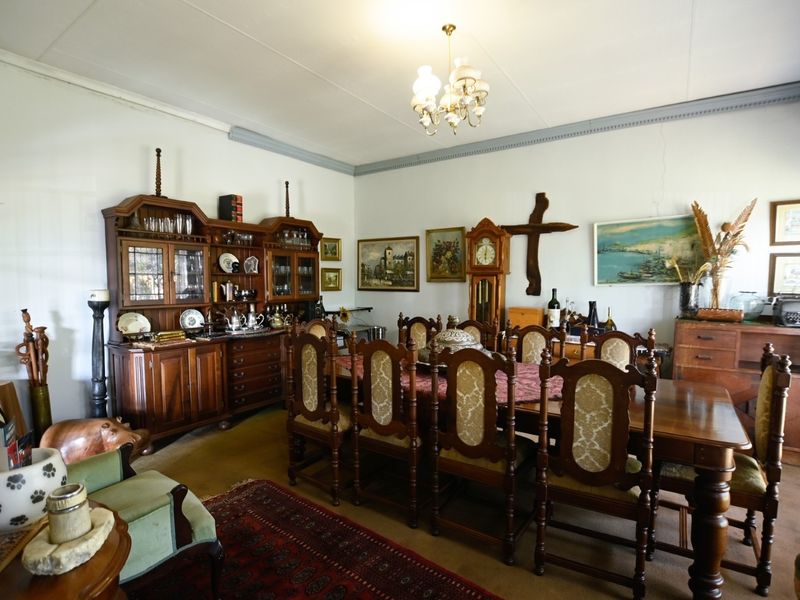 A traditional dining room featuring classic crown molding, a central chandelier, and visible wall cracks requiring maintenance.