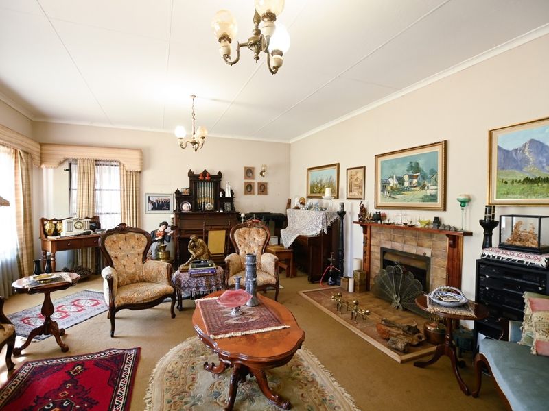 A traditional living room featuring a fireplace with a timber mantelpiece, coved ceilings, and carpeted flooring.