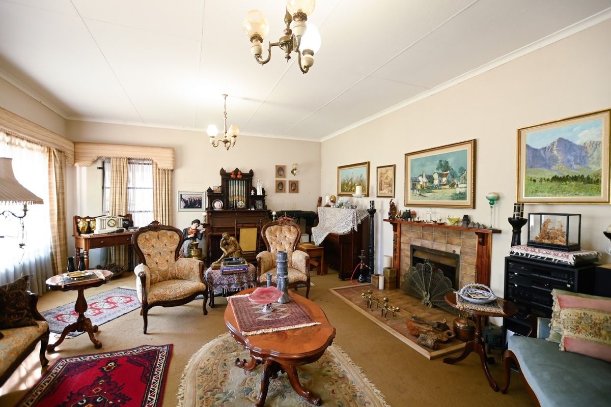 A traditional living room featuring a fireplace with a timber mantelpiece, coved ceilings, and carpeted flooring.