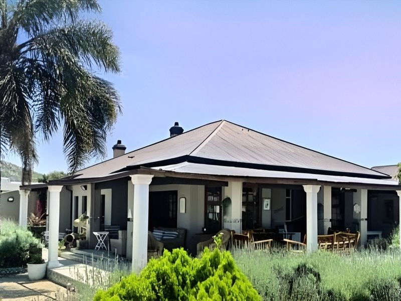 A spacious covered patio area featuring structural columns and a metal roof, providing an ideal outdoor living space overlooking the garden.