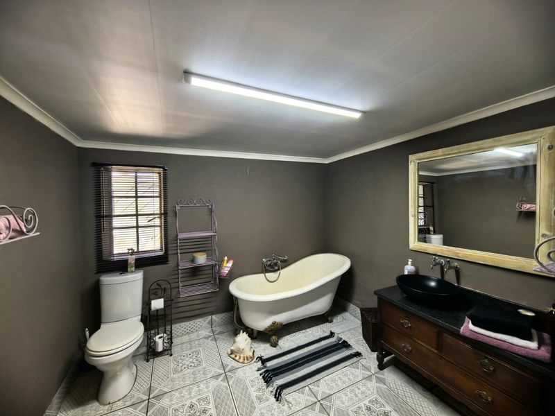 A bathroom featuring a classic clawfoot bathtub, a dark wood vanity with a vessel sink, and patterned floor tiles.
