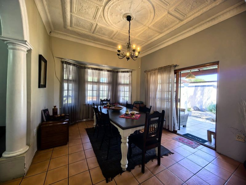 Dining room featuring a decorative pressed metal ceiling with a central rose, terracotta tiled flooring, and direct access to an outdoor patio area.