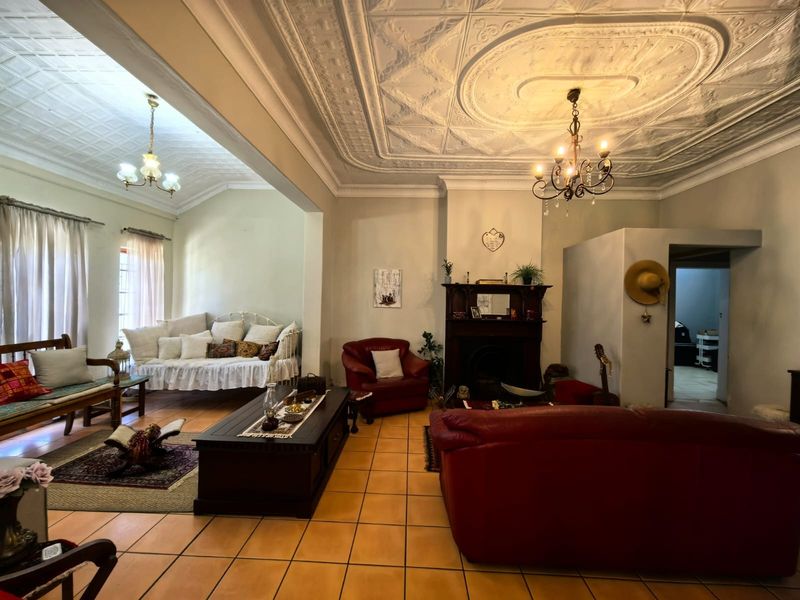Spacious living room featuring a classic ornate pressed metal ceiling, a traditional fireplace with a timber mantel, and durable tiled flooring.