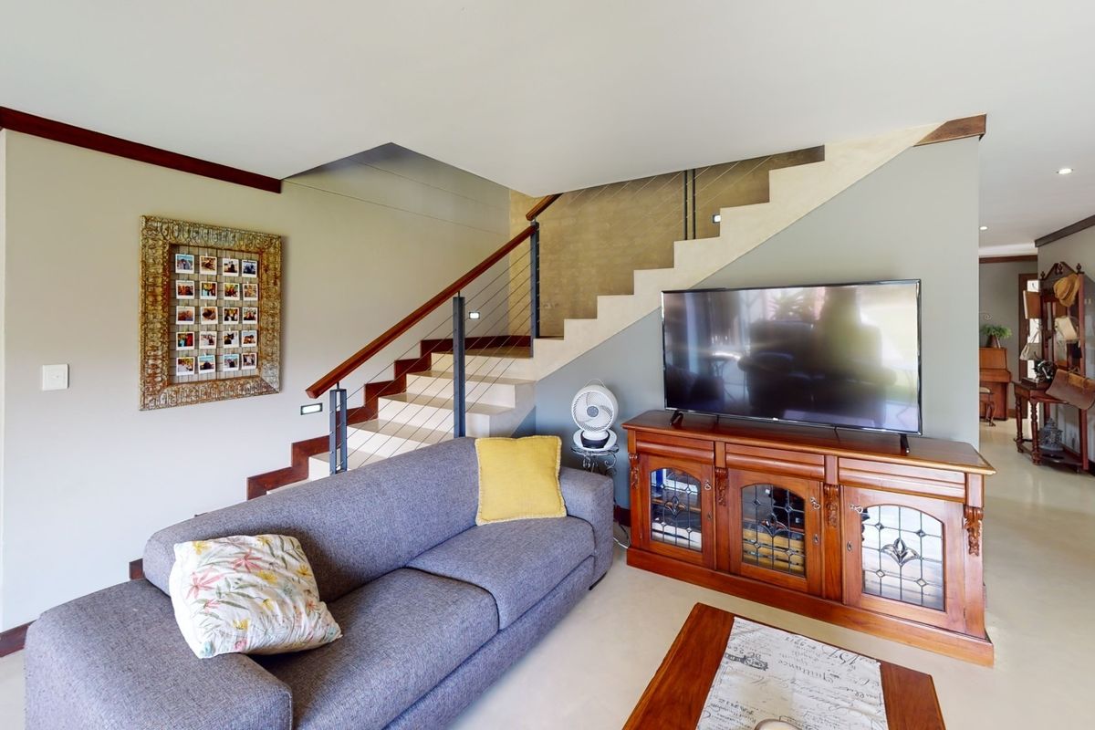 A spacious living area featuring a modern staircase with cable balustrades, built-in shelving, and a sliding barn door leading to adjacent rooms.