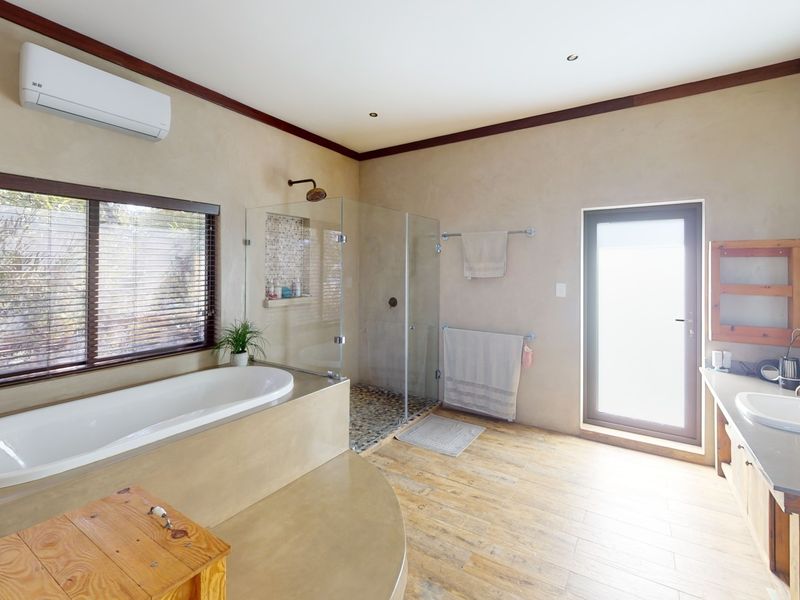 Spacious bathroom featuring a built-in bathtub, glass-enclosed shower, vanity with sink, and wall-mounted air conditioning unit with modern finishes.