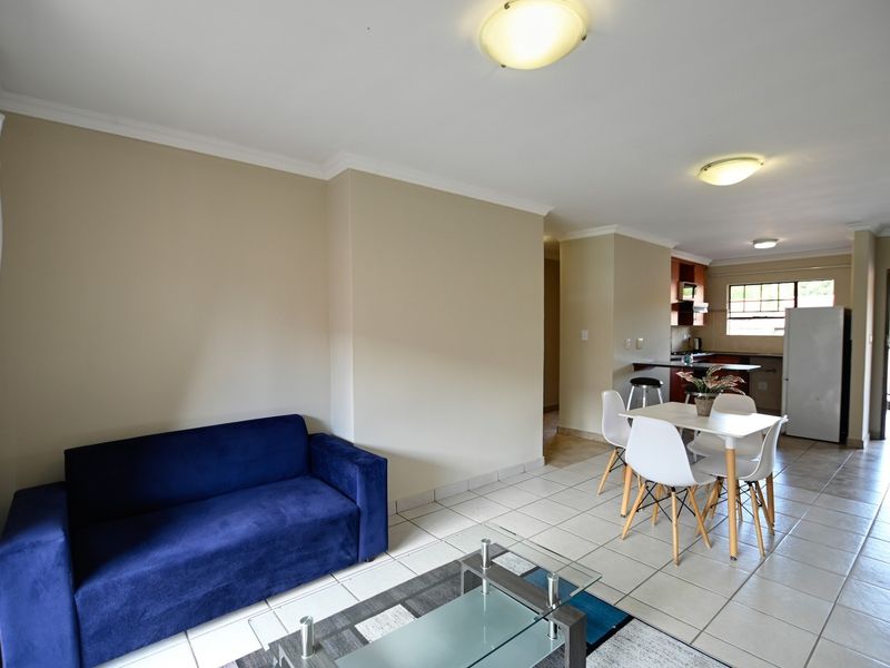 Open-plan living and dining area featuring tiled flooring and a functional kitchen space with built-in cabinetry.
