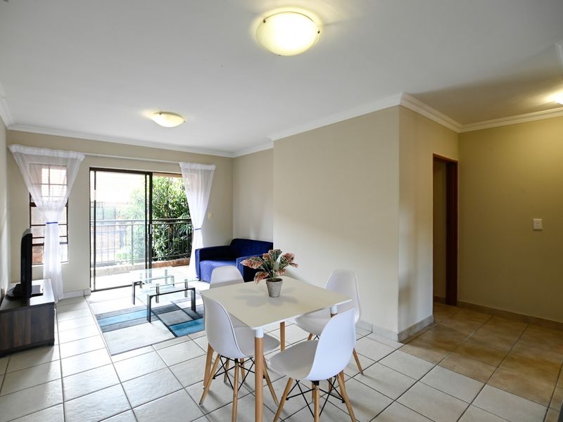 Open plan living and dining area featuring tiled flooring, coved cornicing, and a sliding glass door providing access to the balcony.