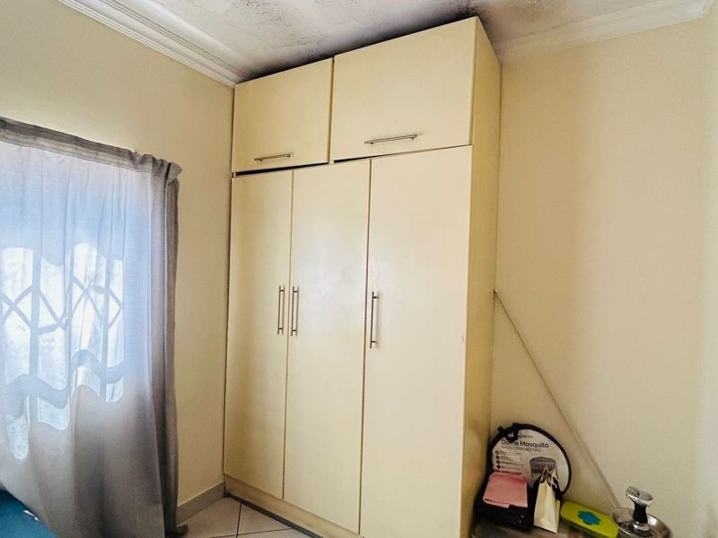 Bedroom featuring a floor-to-ceiling built-in wardrobe with overhead storage and tiled flooring.