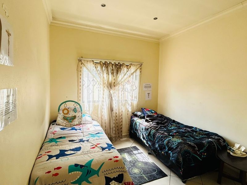 A functional bedroom featuring tiled flooring, recessed downlighting, and security bars on the window.