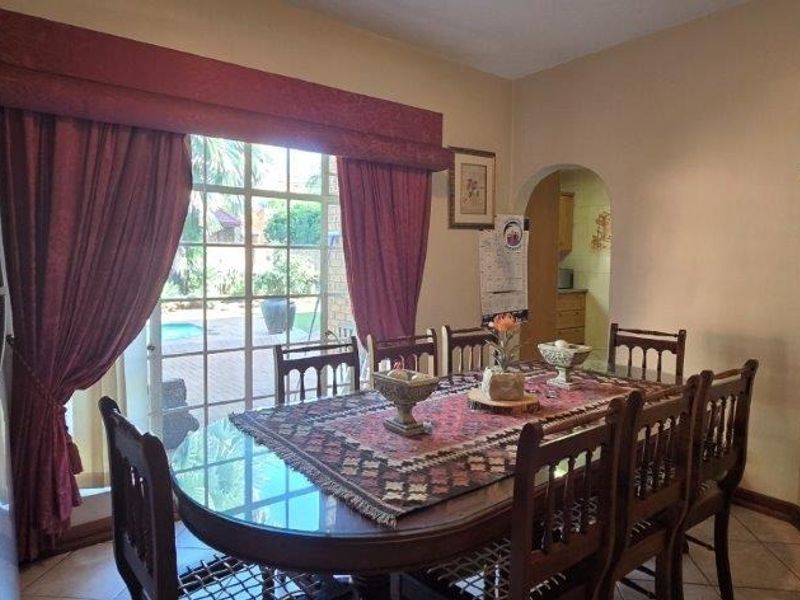 Dining room featuring tiled flooring, an arched doorway leading to the kitchen, and a sliding glass door providing access to the garden.