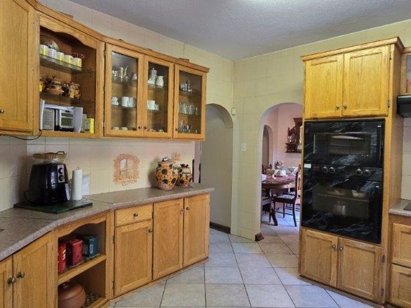 A traditional kitchen featuring oak cabinetry, built-in double oven, gas hob, and tiled finishes, offering a functional layout with potential for modern updates.