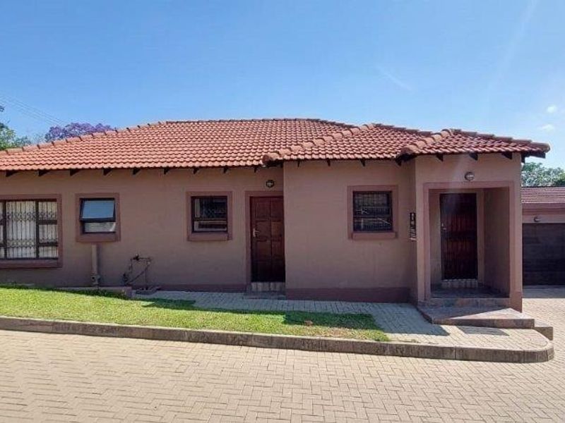 Front elevation of a townhouse featuring a tiled roof, paved driveway, and secure garage access.
