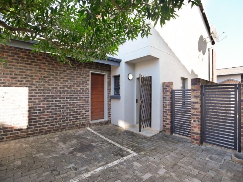 Front entrance area of the townhouse featuring brick paving, a secure gated access point, and a combination of brick and rendered wall finishes.