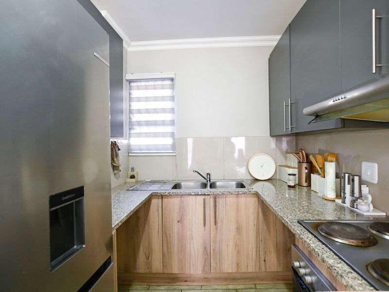 A modern, well-maintained kitchen featuring granite countertops, two-tone cabinetry, a double stainless steel sink, and integrated cooking appliances.