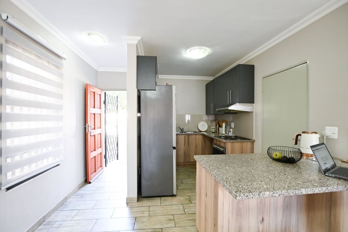 A functional kitchen featuring granite countertops, built-in cabinetry, and integrated appliances, with direct access to the exterior through a secure entrance.