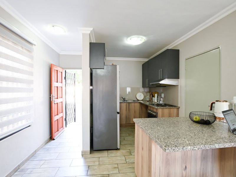 A functional kitchen featuring granite countertops, built-in cabinetry, and integrated appliances, with direct access to the exterior through a secure entrance.