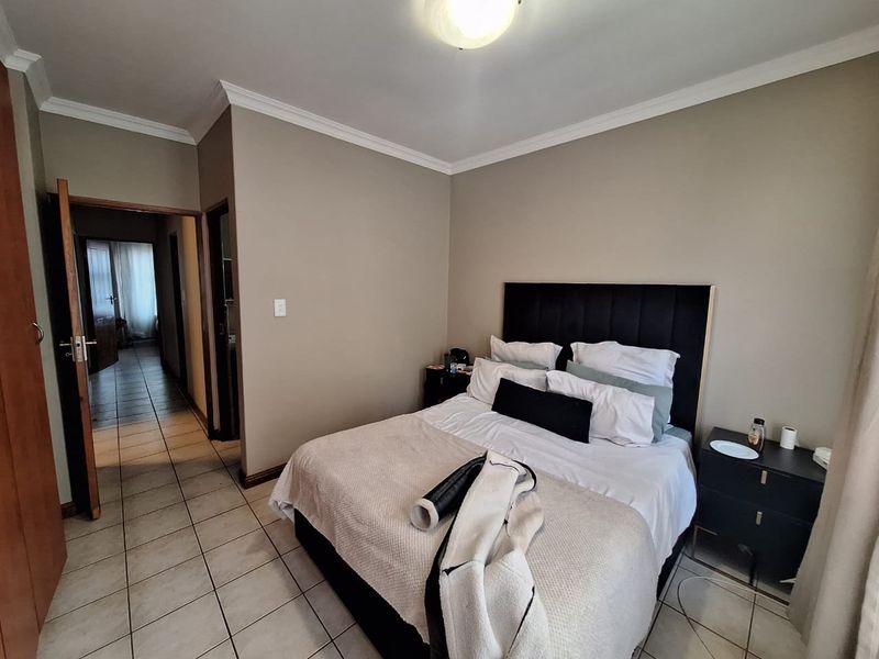 A functional bedroom featuring tiled flooring and neutral wall tones, providing a clean and simple space with direct access to the hallway.