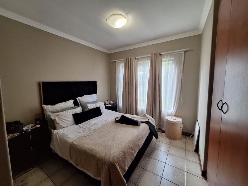 A bedroom featuring tiled flooring, a built-in wardrobe, and neutral wall tones, offering a functional space with natural light.