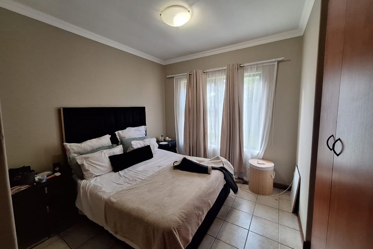 A bedroom featuring tiled flooring, a built-in wardrobe, and neutral wall tones, offering a functional space with natural light.