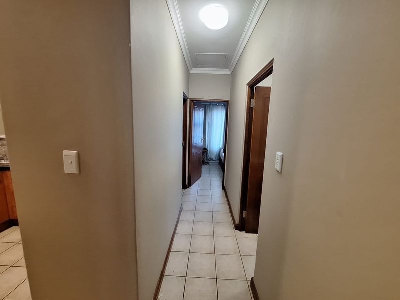 A functional hallway featuring tiled flooring, timber door frames, and ceiling cornice, providing access to adjacent rooms within the townhouse.