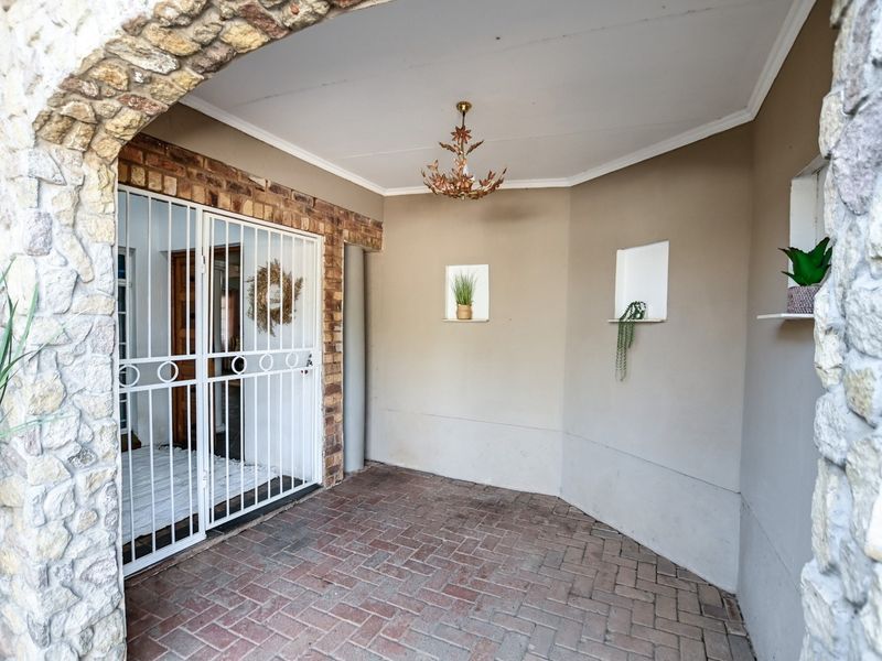A covered patio area featuring brick paving, a stone archway entrance, and built-in wall niches, providing a secure and welcoming outdoor space.