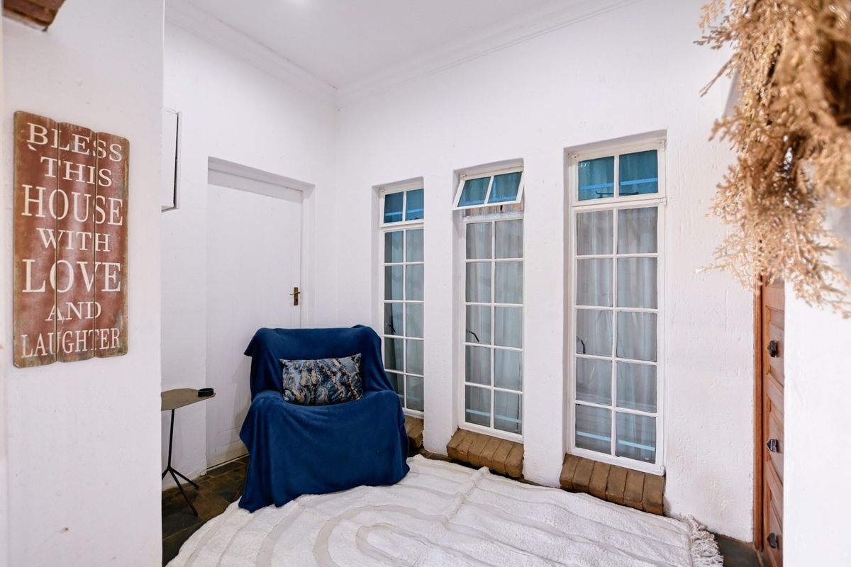 A bright living area featuring white walls, coved ceilings, and a series of multi-pane windows providing natural light.