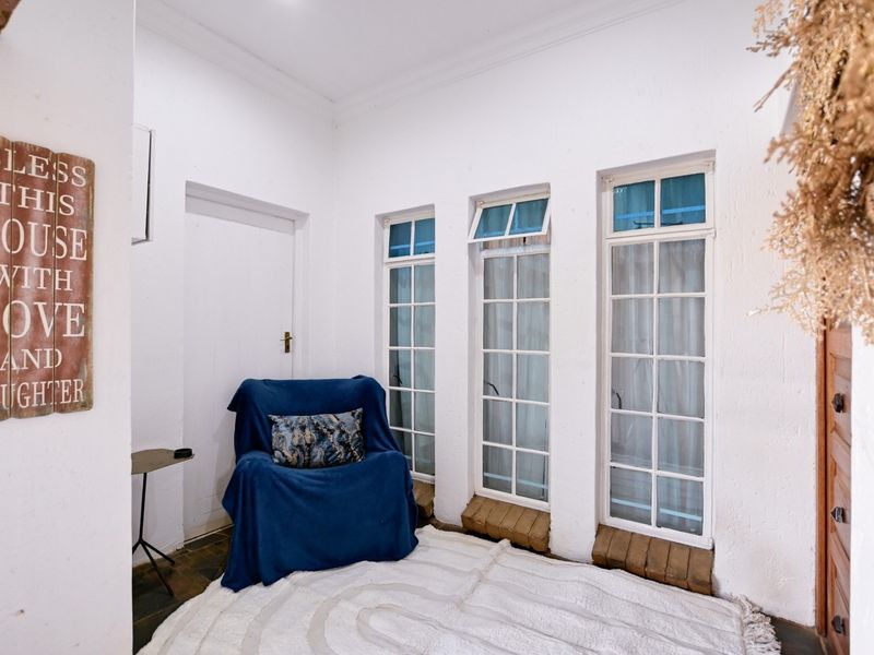 A bright living area featuring white walls, coved ceilings, and a series of multi-pane windows providing natural light.