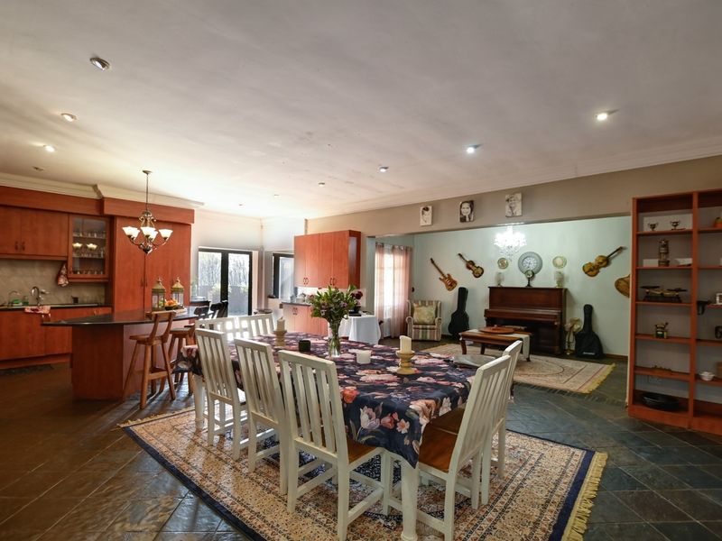 Spacious open-plan living and dining area featuring a large kitchen with built-in cabinetry, stone countertops, and slate tile flooring throughout.