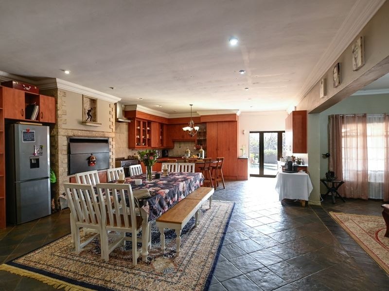 Spacious open-plan living and dining area featuring tiled floors, a stone fireplace, and built-in cabinetry, with direct access to the outdoor patio.