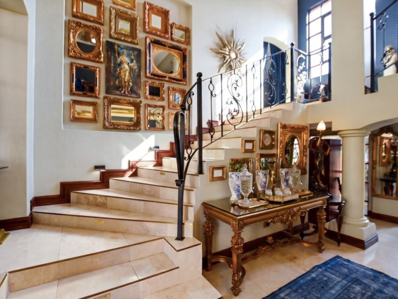 Grand entrance hall featuring a stone staircase with an ornate wrought iron balustrade and polished tiled flooring.