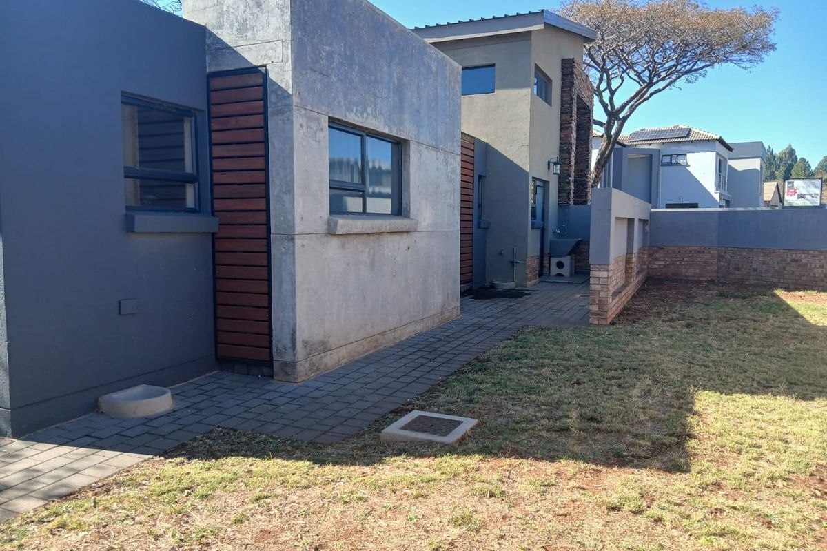 Rear exterior view of the duet property featuring a paved walkway, modern concrete and timber facade, and a private garden area.