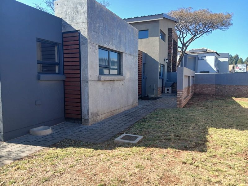 Rear exterior view of the duet property featuring a paved walkway, modern concrete and timber facade, and a private garden area.