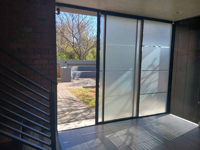 A bright, modern transition space featuring large sliding glass doors that open onto a paved outdoor patio area with a brick feature wall.