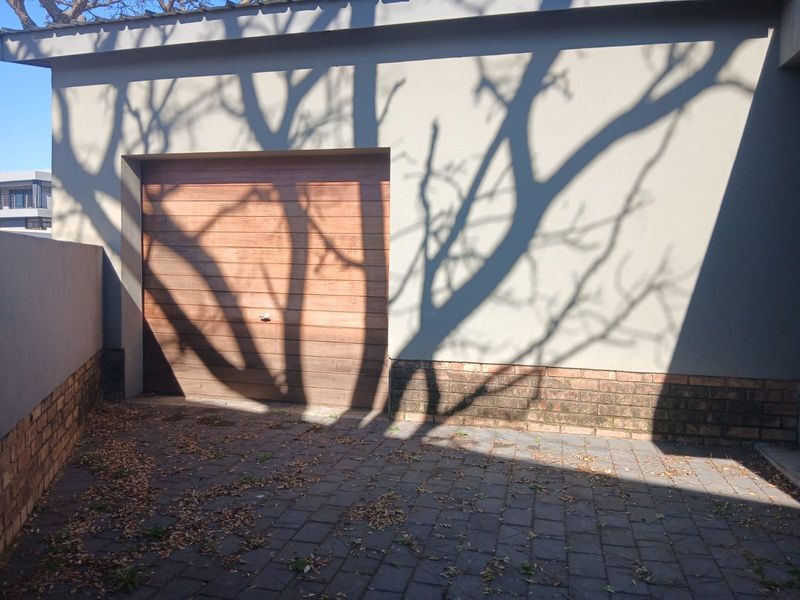 Exterior view of a garage featuring a wooden door and brick paved driveway area.