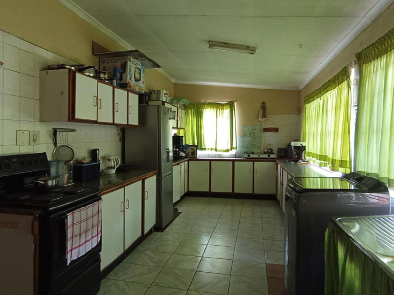 A functional kitchen featuring tiled flooring, built-in cabinetry, a freestanding stove, and a double sink, offering potential for a modern renovation.