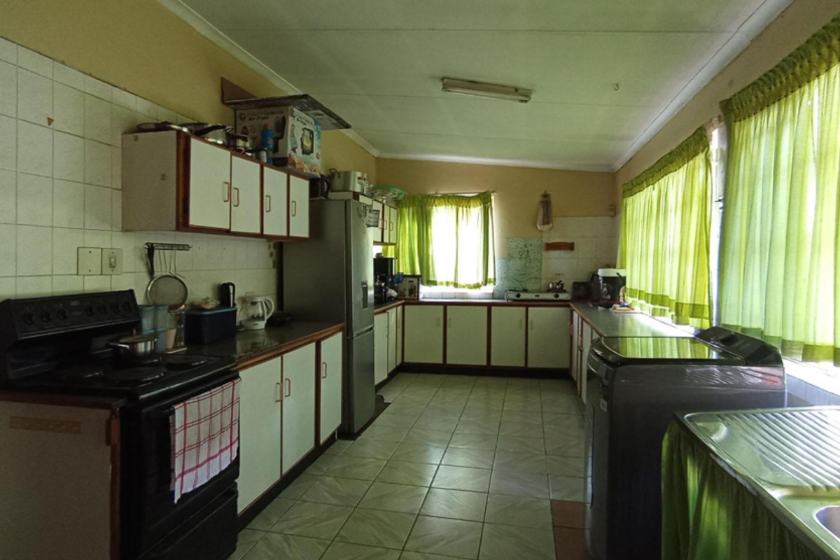 A functional kitchen featuring tiled flooring, built-in cabinetry, a freestanding stove, and a double sink, offering potential for a modern renovation.