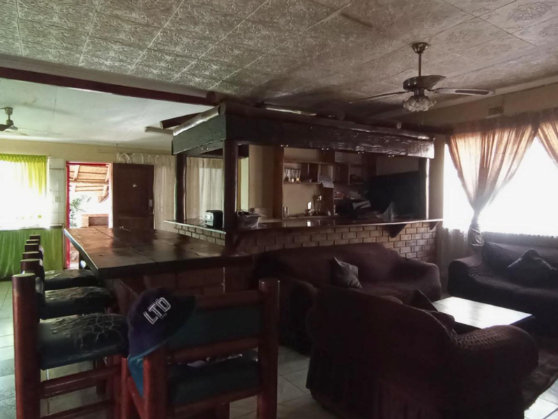 Open plan living area featuring a built-in brick bar, tiled flooring, and a ceiling fan, offering a functional space for entertaining.