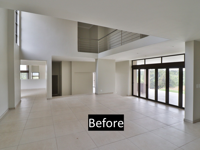 Spacious, light-filled open plan living area featuring double volume ceilings, large folding glass doors leading outdoors, and a mezzanine level with a modern balustrade.