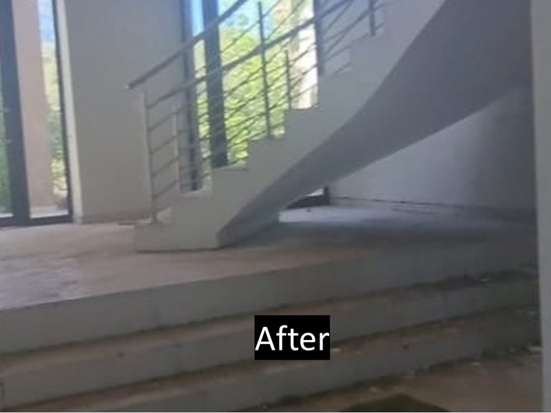 An unfinished entry foyer featuring a concrete staircase with a metal balustrade, large glass doors, and tiled flooring in need of completion.