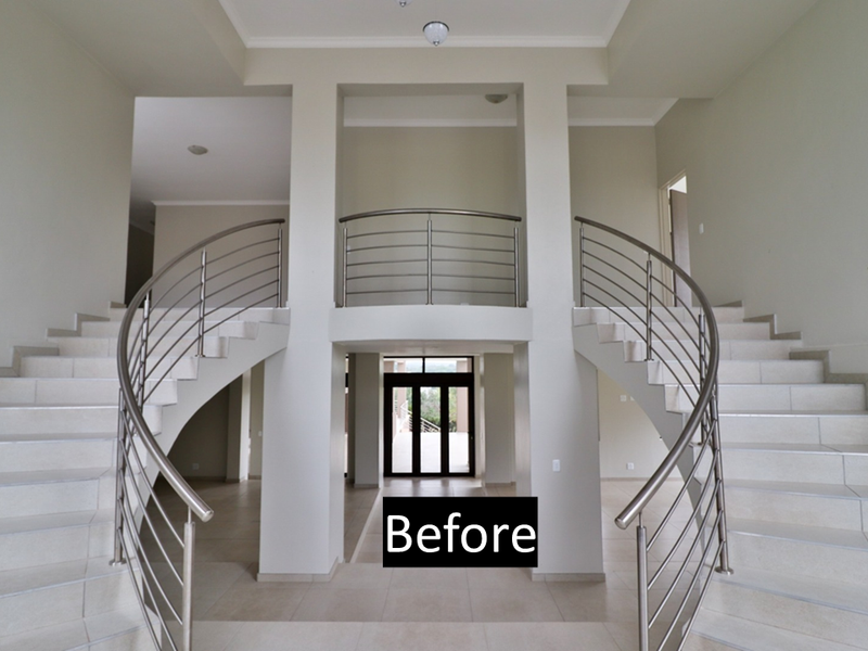 Grand entrance hall featuring dual curved staircases with stainless steel balustrades and neutral tiled flooring, creating an open and spacious architectural focal point.