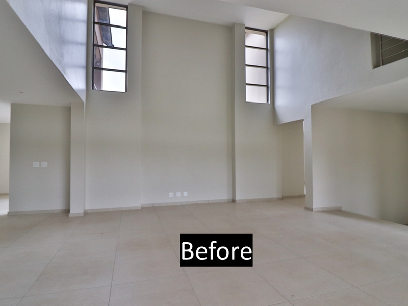 Spacious, light-filled living area featuring double-volume ceilings, large vertical windows, and neutral tiled flooring, offering a versatile open-plan layout.